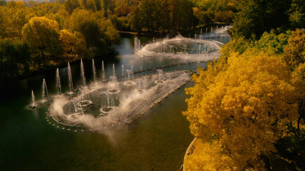 Cadre filmate cu drona în Parcul IOR, București — plan general cu lacul și coroanele de toamnă